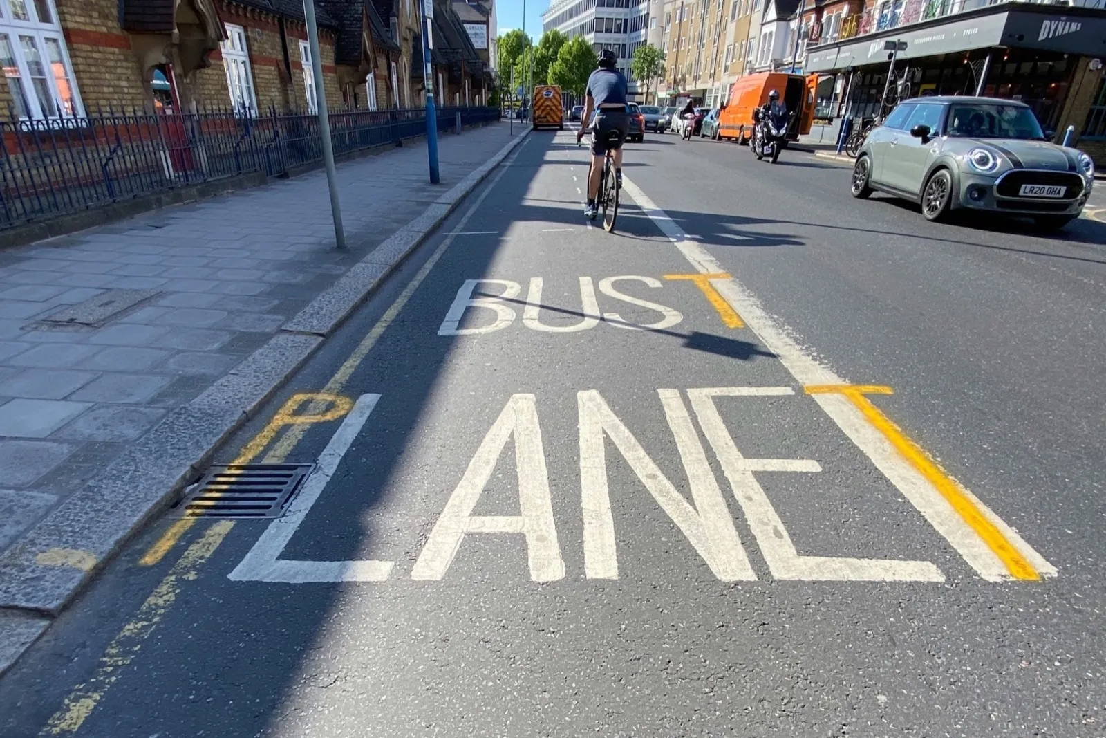 BUS LANE lettering painted on a London road with a cyclist riding in the lane
