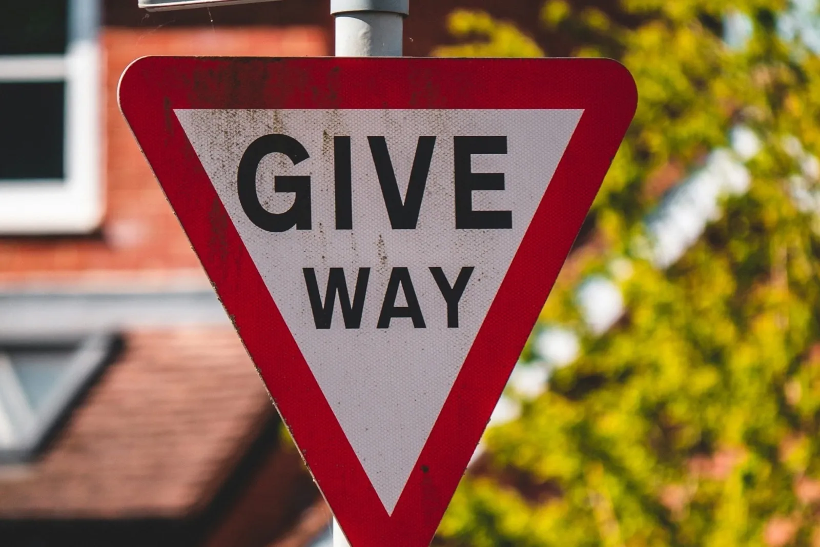 A GIVE WAY sign in front of a brick house